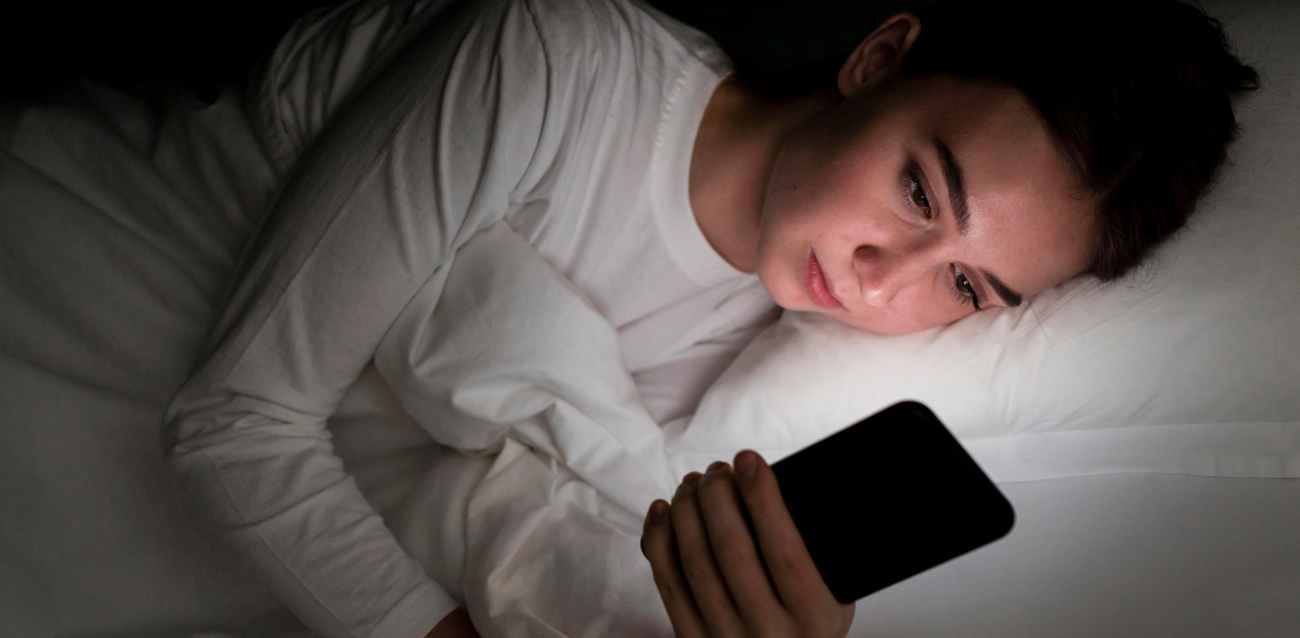 Young woman in bed staring at her phone
